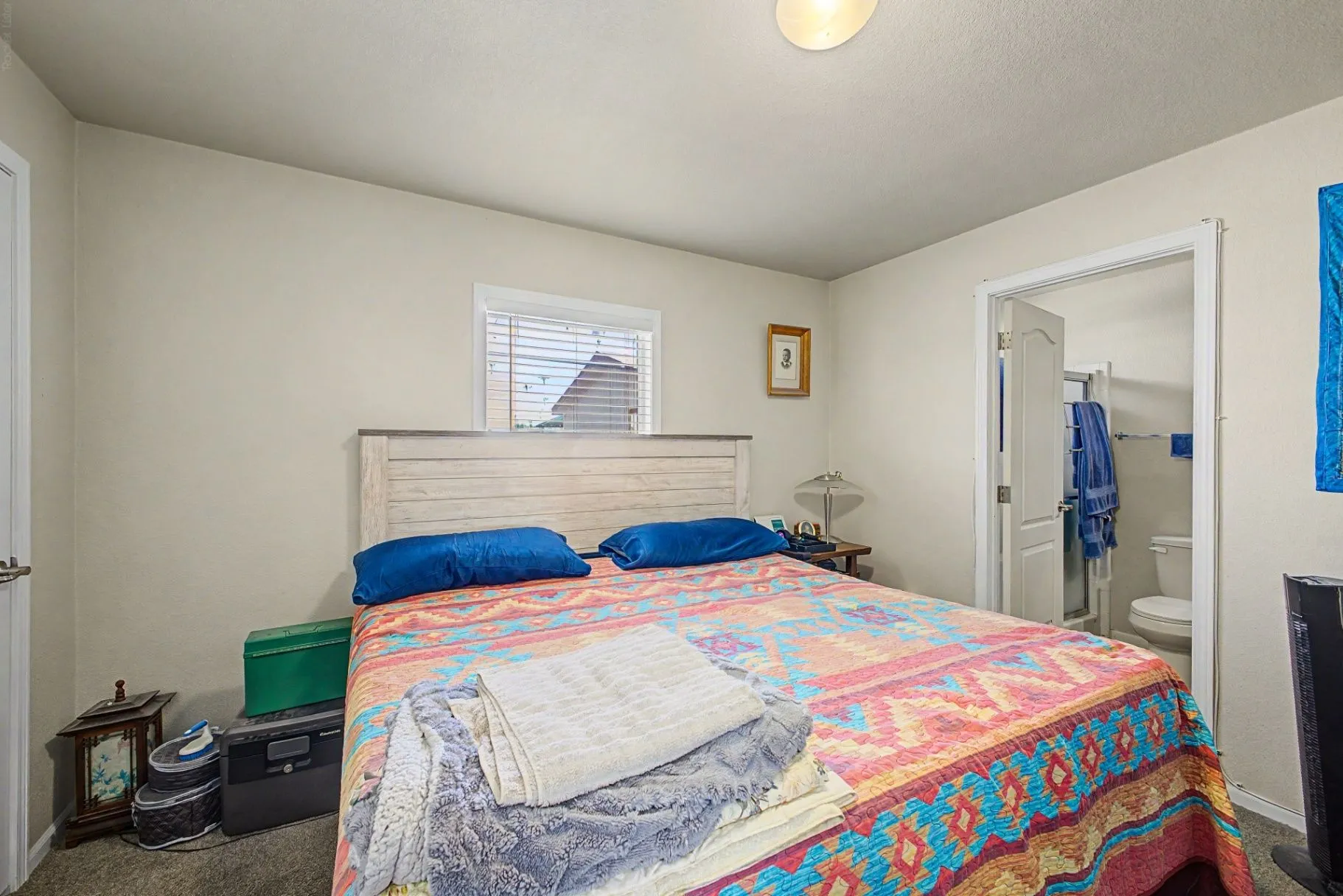 Bedroom with a patterned quilt, dresser, and adjoining bathroom doorway